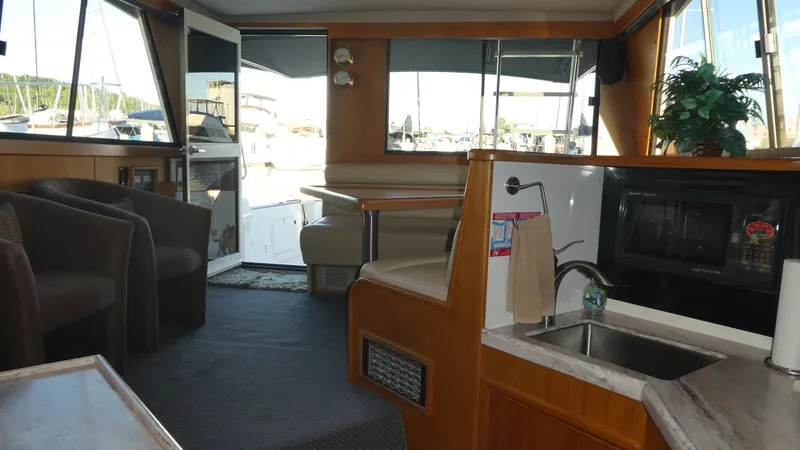 Slide: The Image of Interior of a 1995 Riviera Convertible yacht with seating, kitchenette, and marina view. - 4