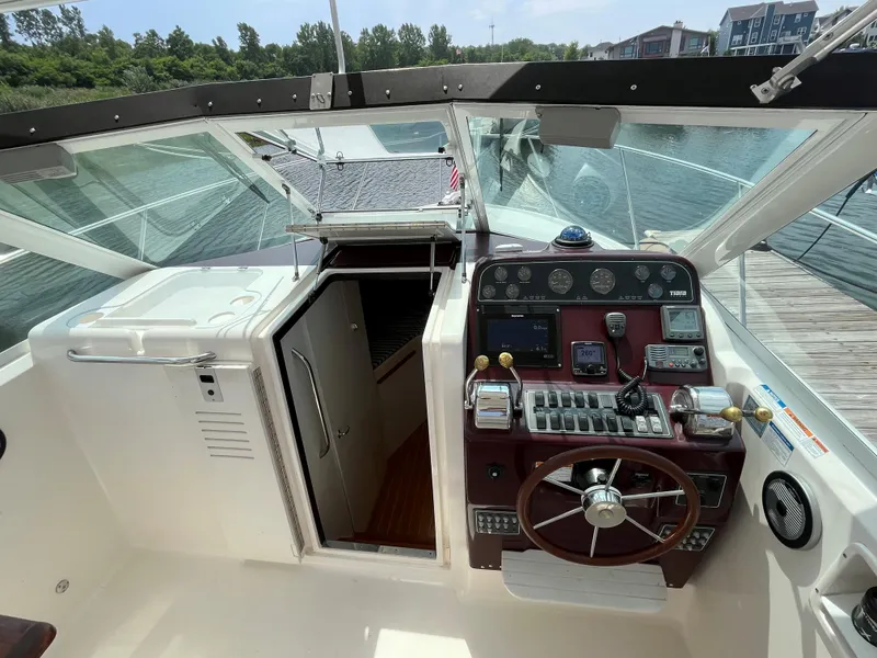 Slide: The Image of 2005 Tiara Yachts 2900 Coronet cockpit with steering wheel and control panel, docked by water. - 10
