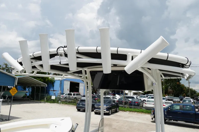 Slide: The Image of T-top of 2026 May-Craft 220 Bay boat with rod holders, under cloudy sky. - 22