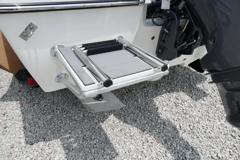 Slide: The Image of 2026 May-Craft 220 Bay boat with a foldable swim platform on gravel surface. - 36