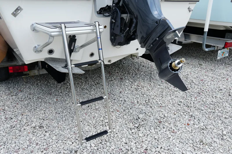 Slide: The Image of 2026 May-Craft 220 Bay boat with ladder and outboard motor on gravel. - 37