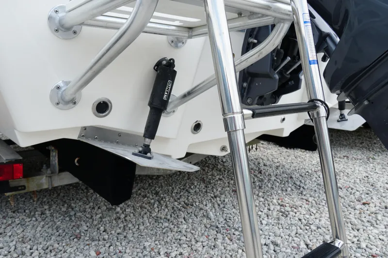 Slide: The Image of 2026 May-Craft 220 Bay boat with stainless steel ladder and trim tab on gravel. - 38