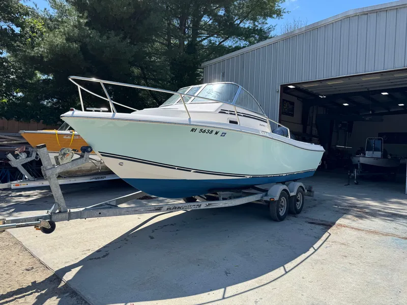 The Image of 2011 Clearwater 21 WAC boat on trailer outside a large garage. - 1