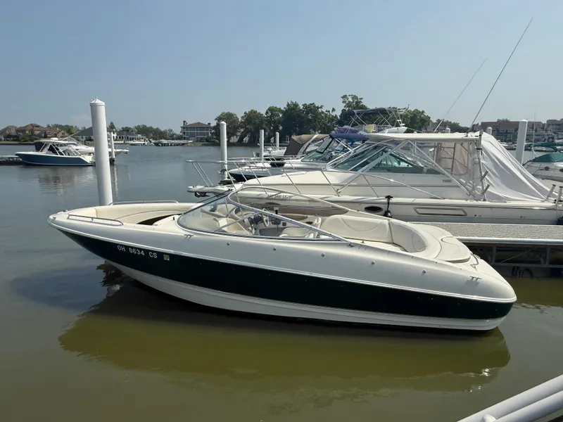 Slide: The Image of 1999 Bayliner 2350 Capri SS boat docked at marina, calm water, clear sky. - 15