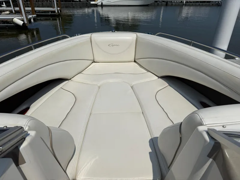 Slide: The Image of 1999 Bayliner 2350 Capri SS boat interior with white cushioned seating at a marina. - 6