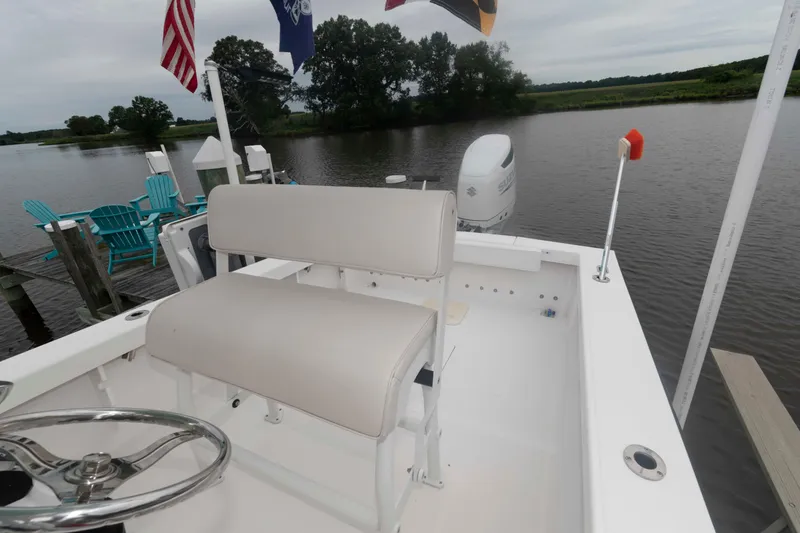 Slide: The Image of 2023 Rambo 27 Center Console boat docked by a serene lake with flags. - 7