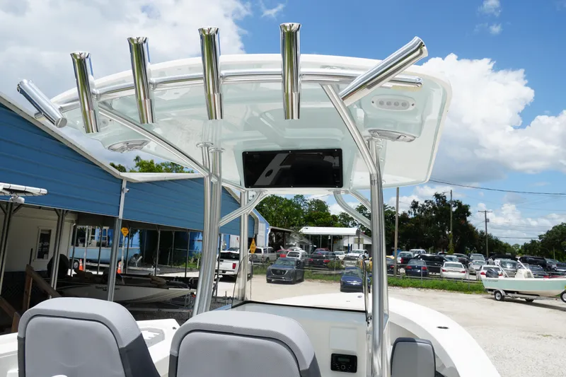 Slide: The Image of 2026 May-Craft 245 Offshore CC boat with T-top and rod holders, parked outdoors. - 13