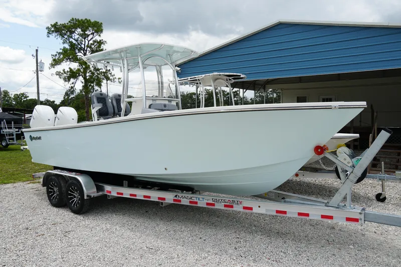 Slide: The Image of 2026 May-Craft 245 Offshore CC boat on trailer, parked outdoors near a blue building. - 37