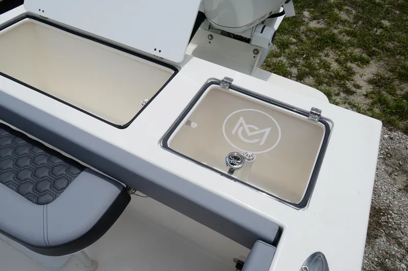 Slide: The Image of 2026 May-Craft 245 Offshore CC boat with open storage compartments and cushioned seating. - 9