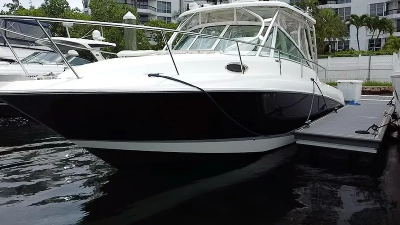 Slide: The Image of 2014 Wellcraft 340 Coastal boat docked at marina, sleek design, white and black exterior. - 2