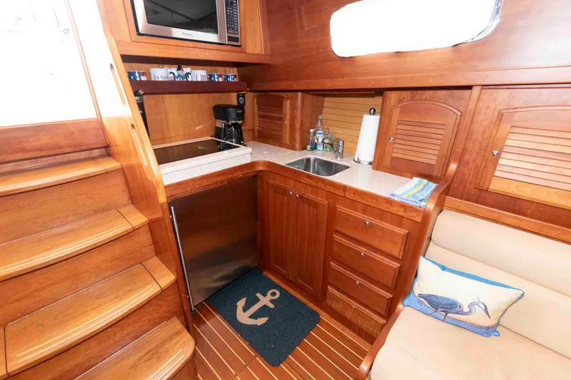 Slide: The Image of 2003 Sabre 42 Express yacht interior with wooden cabinetry, kitchenette, and nautical decor. - 24