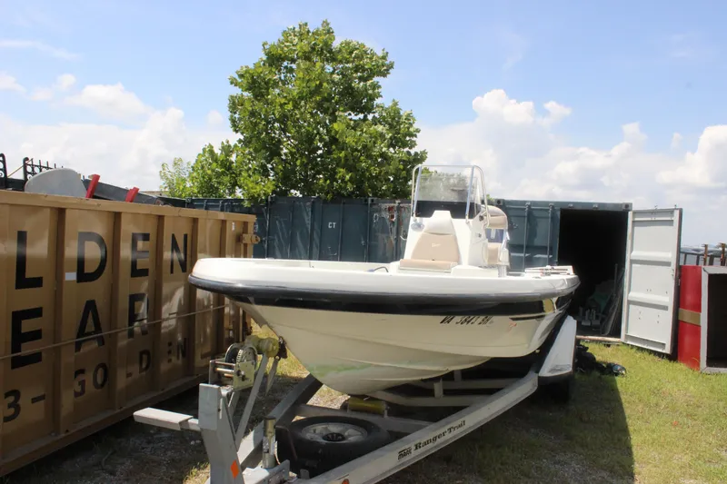 Slide: The Image of 2011 Ranger 2400 Bay Ranger boat on trailer, parked outdoors near storage containers. - 11