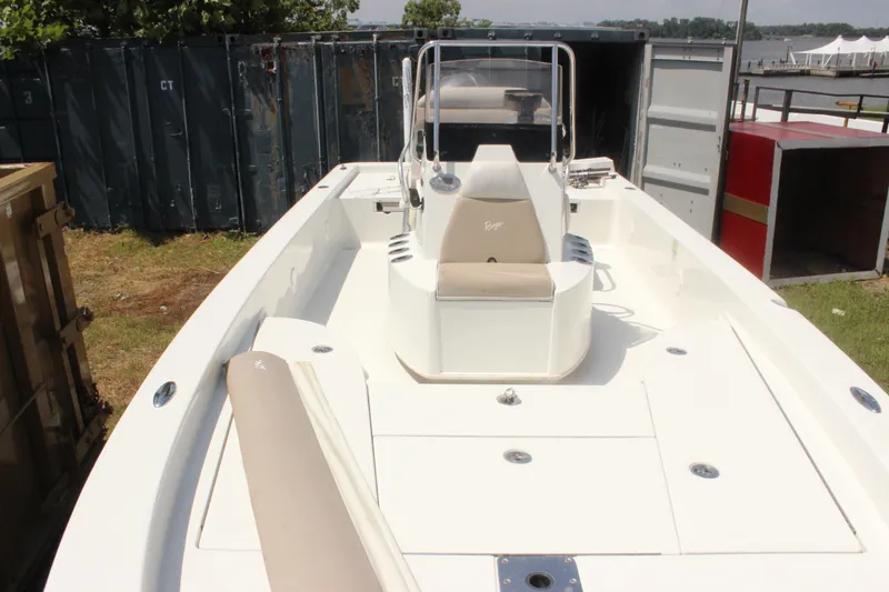 Slide: The Image of 2011 Ranger 2400 Bay Ranger boat with beige seating, docked near storage containers. - 13
