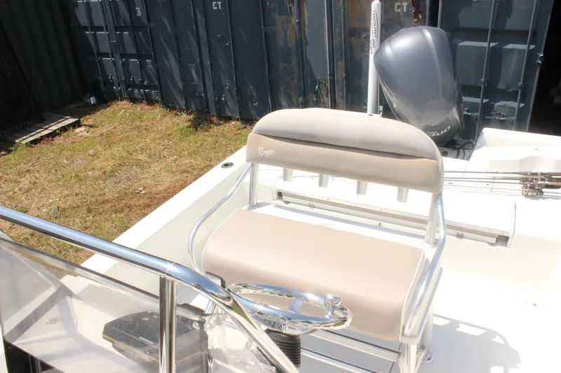 Slide: The Image of 2011 Ranger 2400 Bay Ranger boat interior with seating and motor, docked near containers. - 16