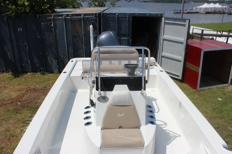 Slide: The Image of 2011 Ranger 2400 Bay Ranger boat docked near a lake with open storage containers. - 24
