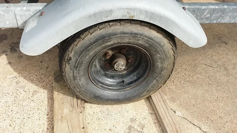Slide: The Image of Trailer wheel of a 1982 Starwind 19 on a wooden track. - 33