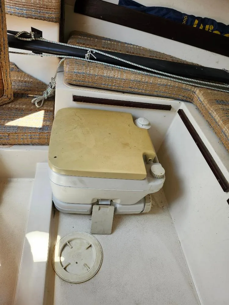 Slide: The Image of Portable toilet inside a 1982 Starwind 19 sailboat cabin with cushioned seating. - 6