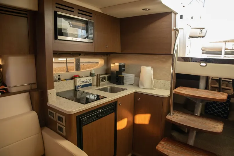 Slide: The Image of 2016 Sea Ray 350 Sundancer galley with microwave, sink, and compact fridge. - 104