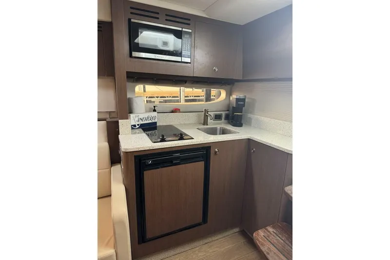 Slide: The Image of 2016 Sea Ray 350 Sundancer yacht kitchen with fridge, microwave, and countertop appliances. - 105