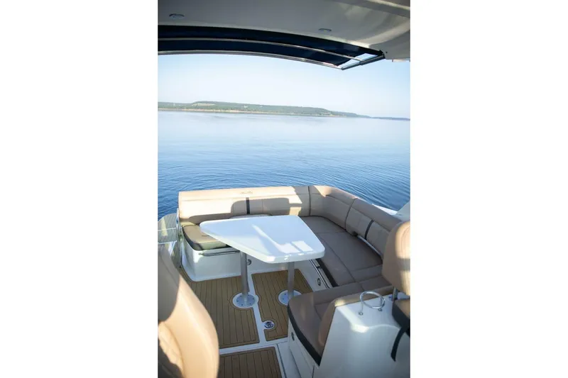 Slide: The Image of 2016 Sea Ray 350 Sundancer boat interior with seating and table, overlooking calm water. - 46