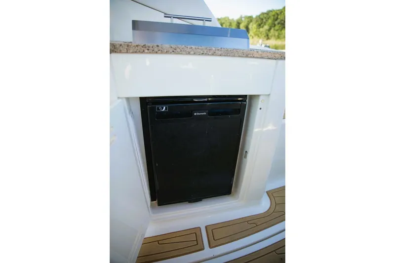 Slide: The Image of 2016 Sea Ray 350 Sundancer interior with TV and kitchenette in a covered marina. - 62