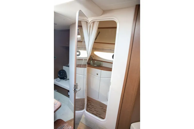 Slide: The Image of 2016 Sea Ray 350 Sundancer boat bathroom with compact toilet and wooden accents. - 96