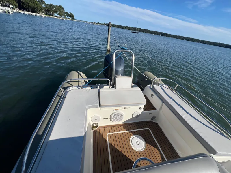 Slide: The Image of 2015 Zodiac N-ZO 760 boat on calm water, featuring spacious deck and seating. - 15