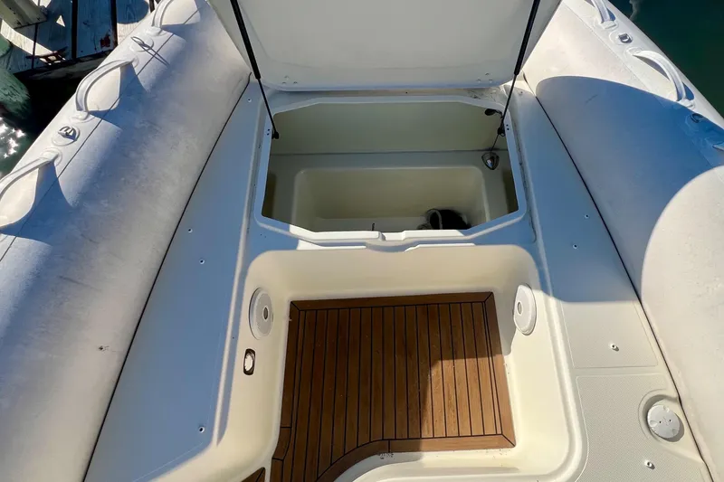 Slide: The Image of 2015 Zodiac N-ZO 760 boat interior with open storage compartment and wooden deck. - 25