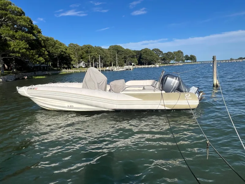 Slide: The Image of 2015 Zodiac N-ZO 760 boat moored on calm water, surrounded by trees and clear blue sky. - 28