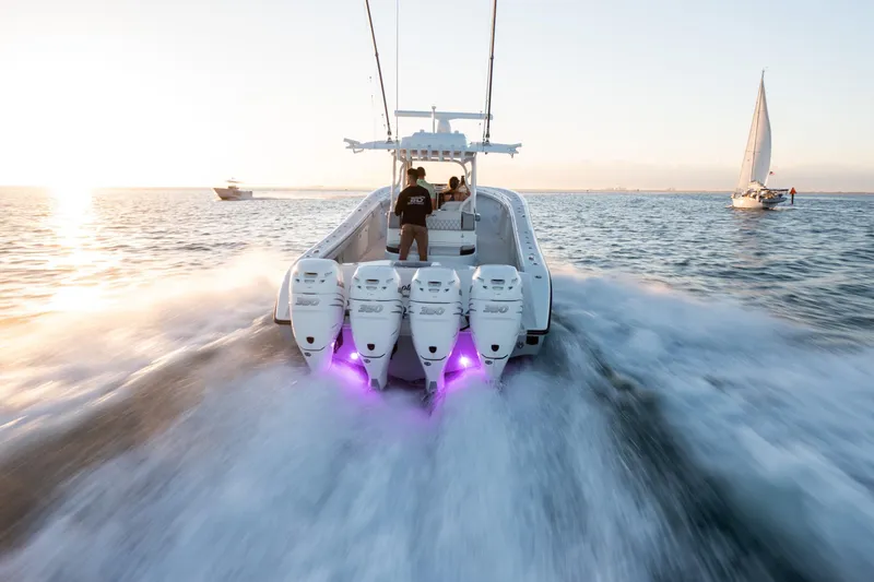 Slide: The Image of 2019 Yellowfin 39 boat speeding on water at sunset with purple lights. - 16