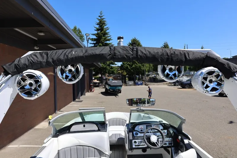 Slide: The Image of 2018 MB B52 23 boat interior with speakers and dashboard, parked outdoors. - 21