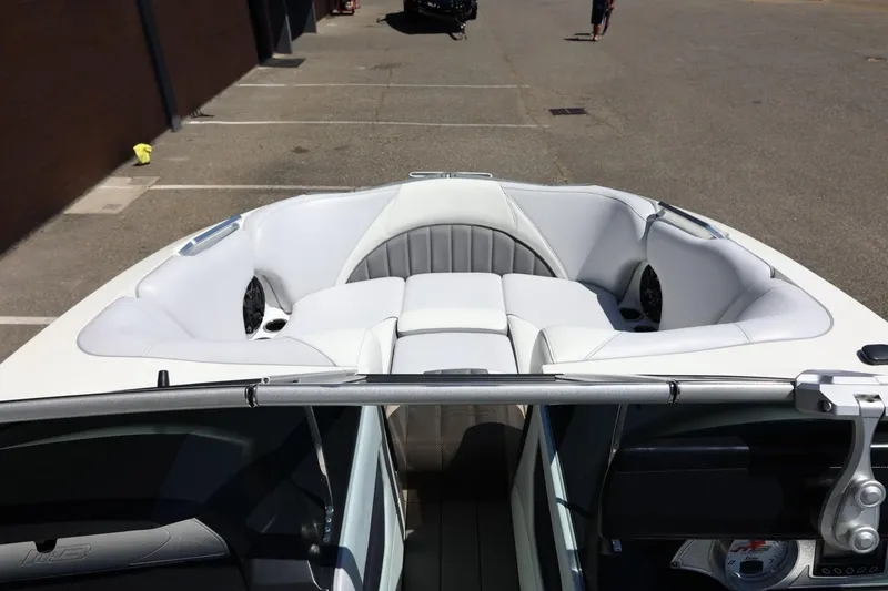 Slide: The Image of 2018 MB B52 23 boat interior with white seating and speakers, parked outdoors. - 32