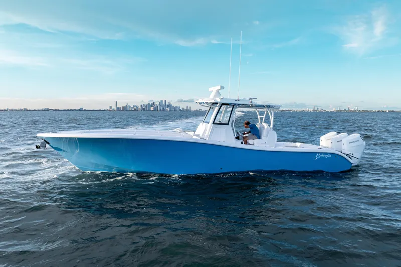 Slide: The Image of 2026 Yellowfin 36 Offshore boat cruising on open water with city skyline backdrop. - 2