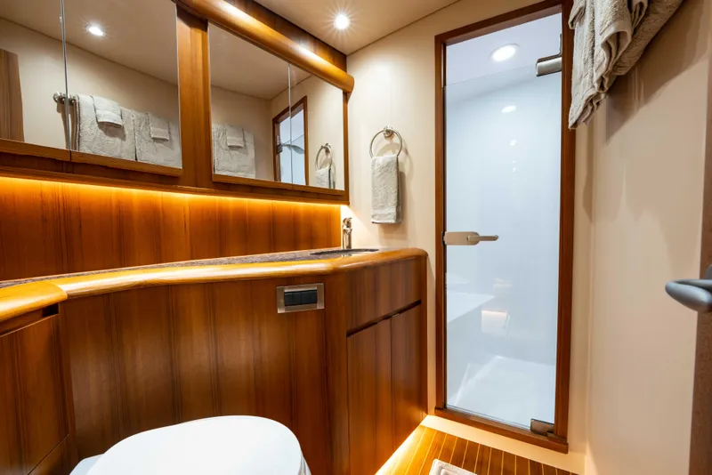 Slide: The Image of Luxurious bathroom interior on 2025 Garlington 71' Flybridge yacht, featuring wood accents and modern fixtures. - 15