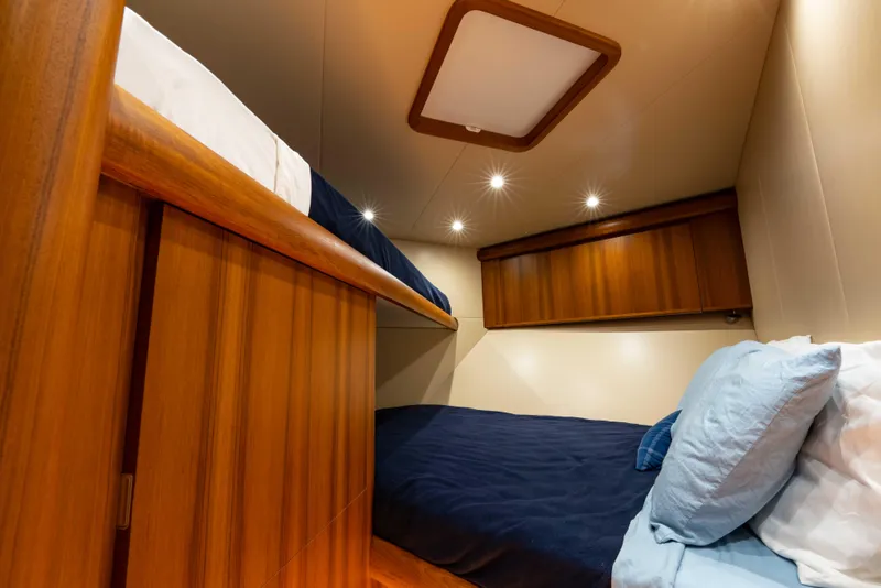 Slide: The Image of Cozy cabin interior of 2025 Garlington 71' Flybridge with wooden finishes and bunk beds. - 18