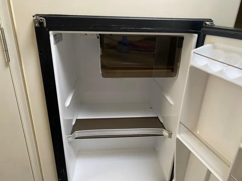 Slide: The Image of Empty refrigerator inside a 2001 Wellcraft 45 Excalibur boat, showing shelves and door compartments. - 19