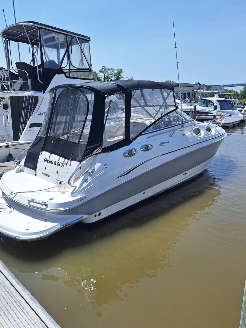 The Image of 2010 Glastron GS 289 boat docked in marina, featuring sleek design and protective canopy. - 0