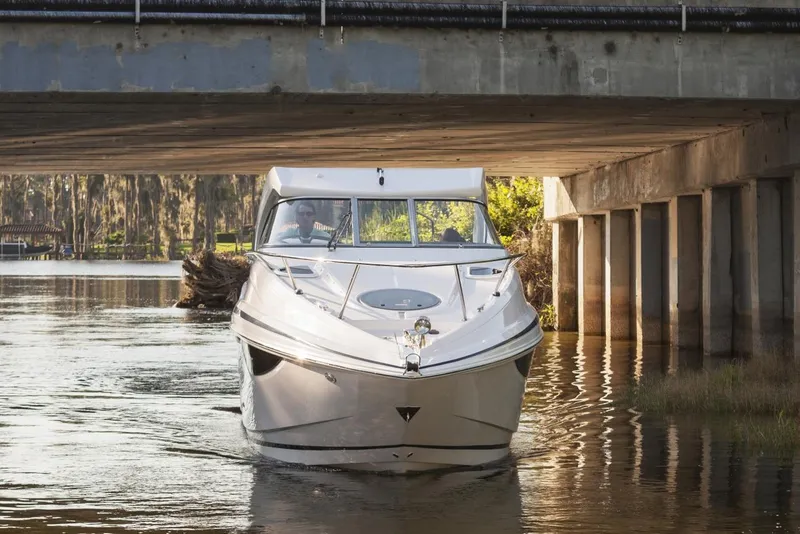 Slide: The Image of 2016 Regal 28 Express boat navigating under a bridge on a calm river. - 87