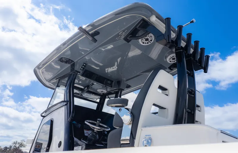 Slide: The Image of 2025 Tidewater 3100 CB boat helm with T-top and rod holders under blue sky. - 9