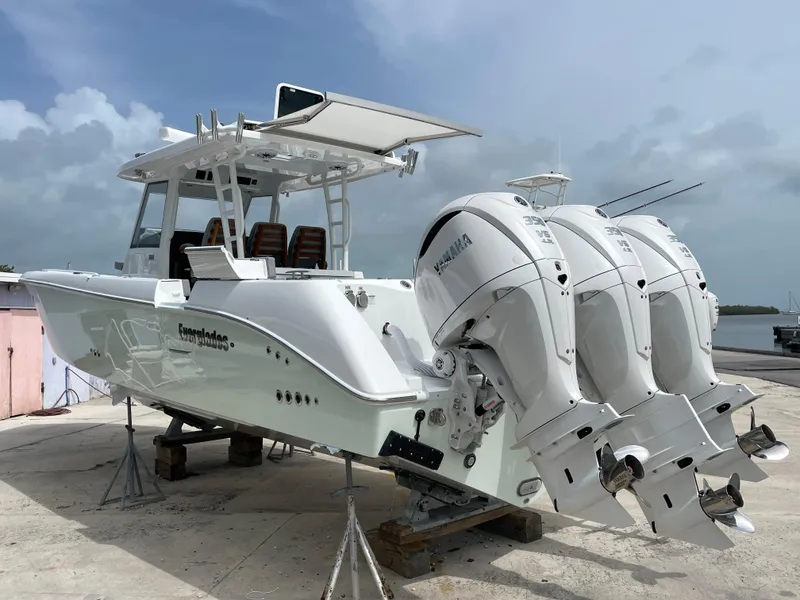 The Image of 2026 Everglades 375cc boat with triple Yamaha outboard engines on a dock. - 1