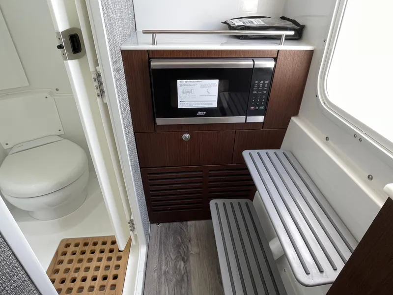 Slide: The Image of Compact boat interior with a microwave, toilet, and seating in the 2026 Everglades 375cc model. - 34