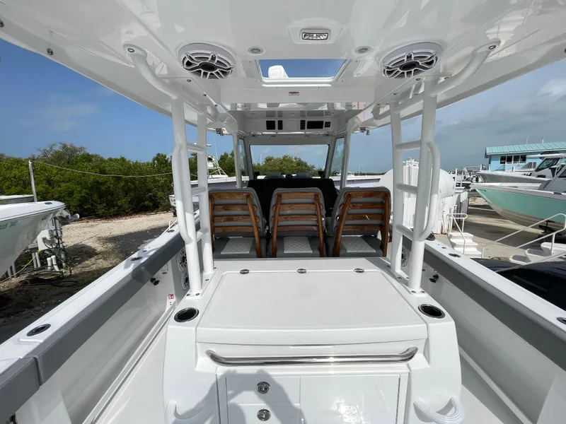 Slide: The Image of 2026 Everglades 375cc boat interior with seating and storage, docked under clear skies. - 44