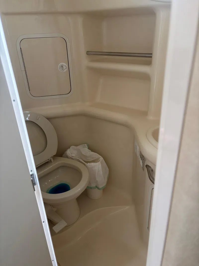 Slide: The Image of Compact bathroom in 2000 Sea Ray 310 Sundancer boat, featuring toilet and storage. - 7