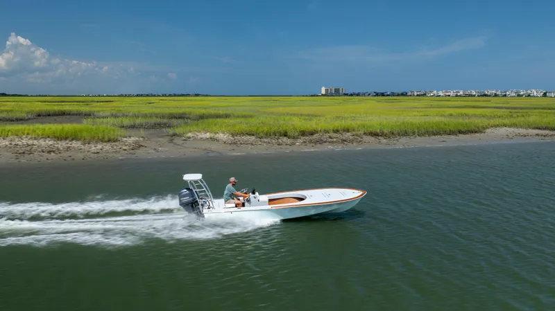 Slide: The Image of 2023 Custom Carolina 18 Flats boat cruising in scenic coastal waters. - 11