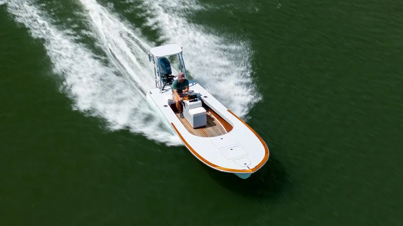 Slide: The Image of 2023 Custom Carolina 18 Flats boat cruising on open water, aerial view. - 15