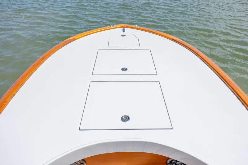 Slide: The Image of Bow of 2023 Custom Carolina 18 Flats boat on water, featuring sleek design and storage hatches. - 17