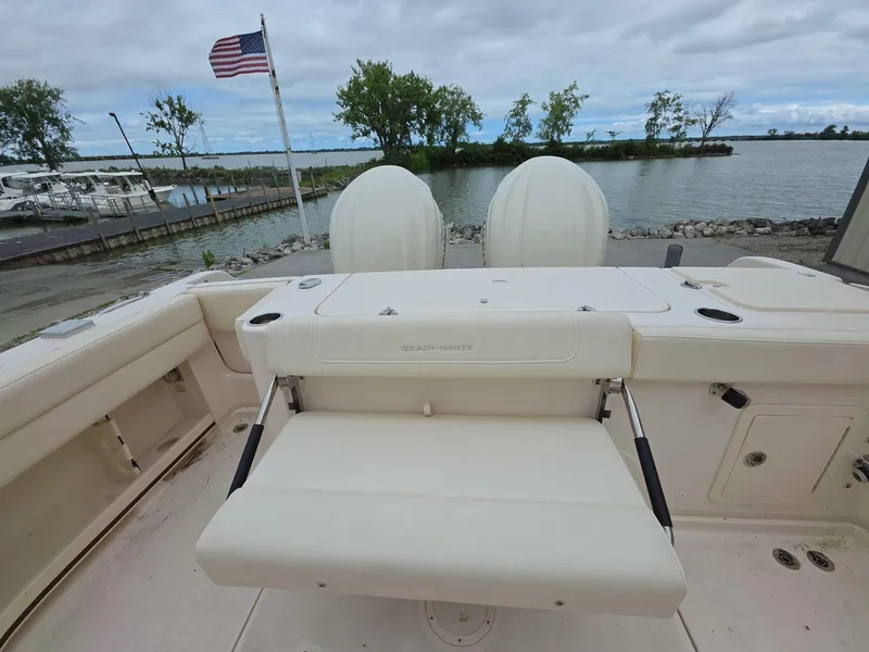 Slide: The Image of 2024 Grady-White Marlin 300 boat interior with seating, docked by a lake. - 15