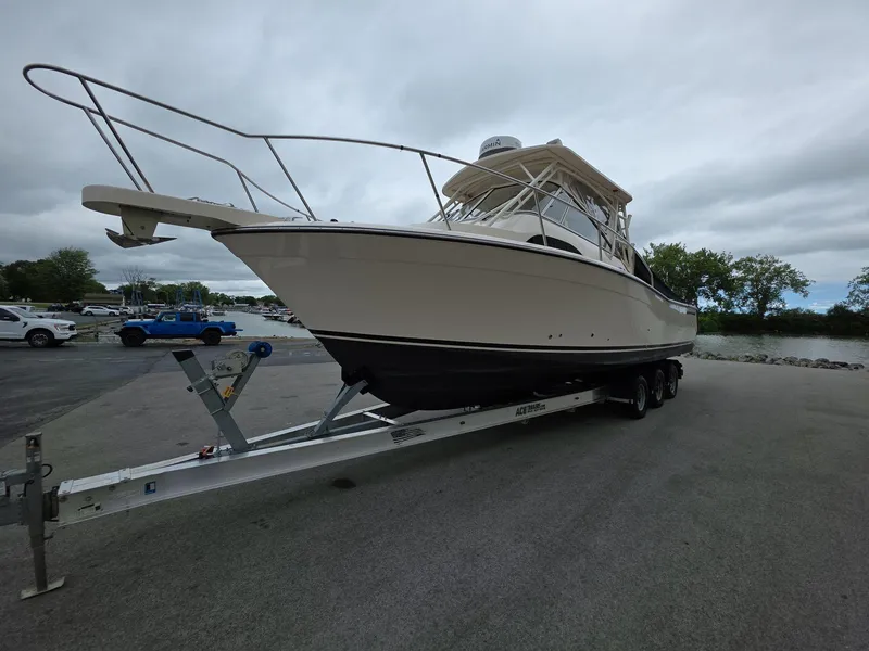 Slide: The Image of 2024 Grady-White Marlin 300 boat on trailer, parked near water under cloudy sky. - 3