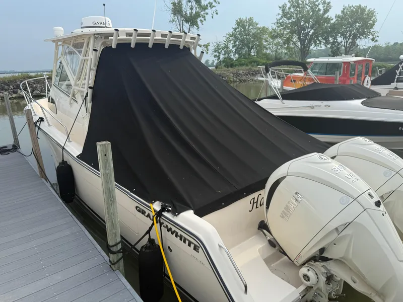 Slide: The Image of 2024 Grady-White Marlin 300 boat docked with black cover and twin Yamaha engines. - 6