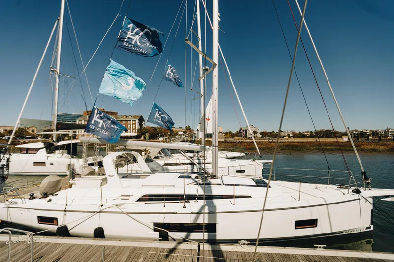Slide: The Image of 2024 Beneteau Oceanis 46.1 yacht docked with flags, under clear blue sky. - 0